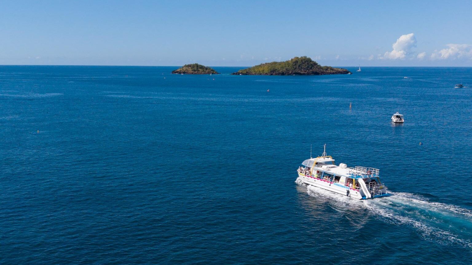 Un bateau à fond de verre des Nautilus navigue sur une mer calme et turquoise en direction des Îlets Pigeon, au cœur de la Réserve Cousteau en Guadeloupe.